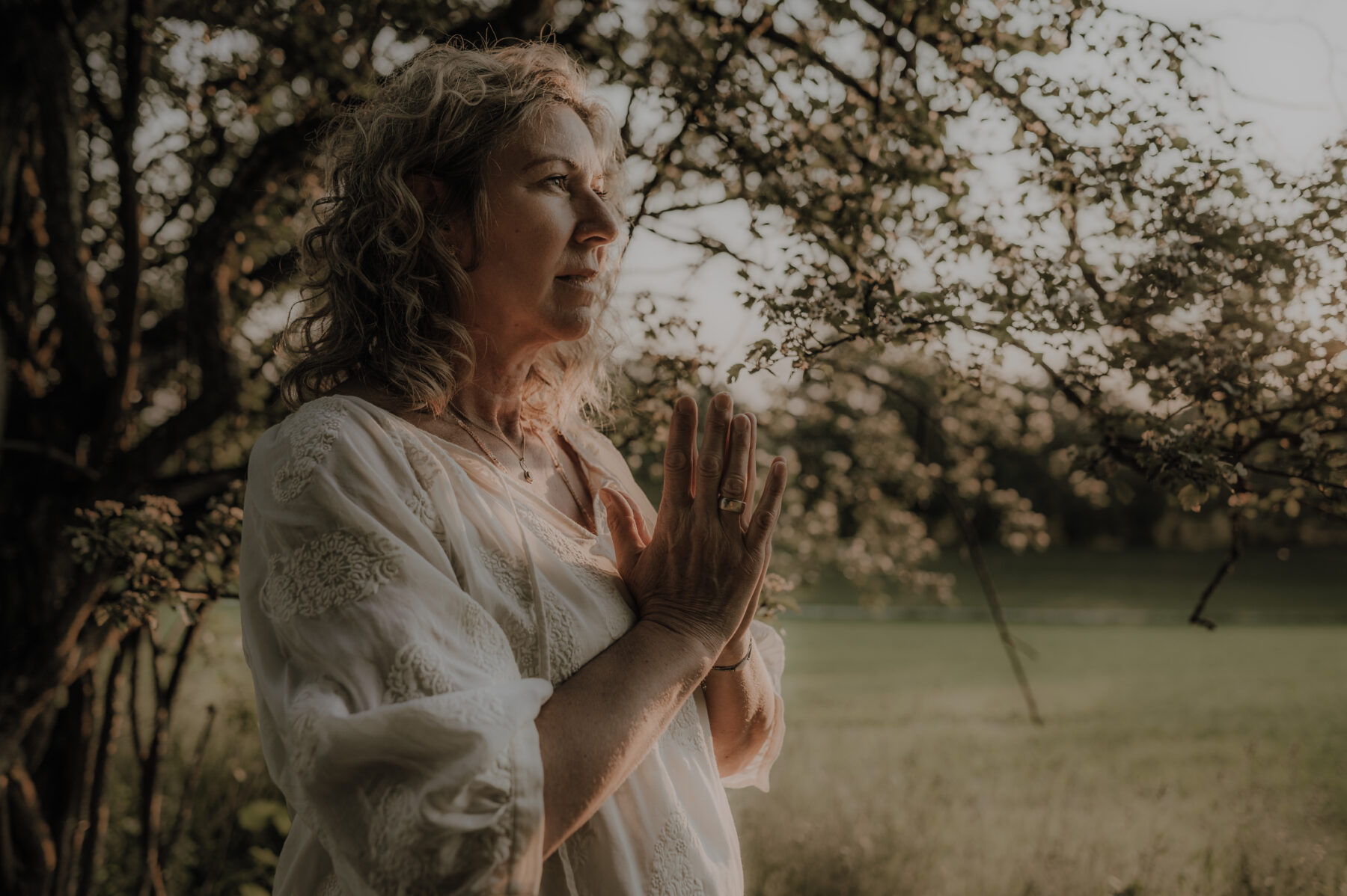 channeling-kurs-ammersee Hildegard Bauer, Channeling Expertin, mit betenden Händen in der Natur bereitet sich auf ihren Kurs vor.