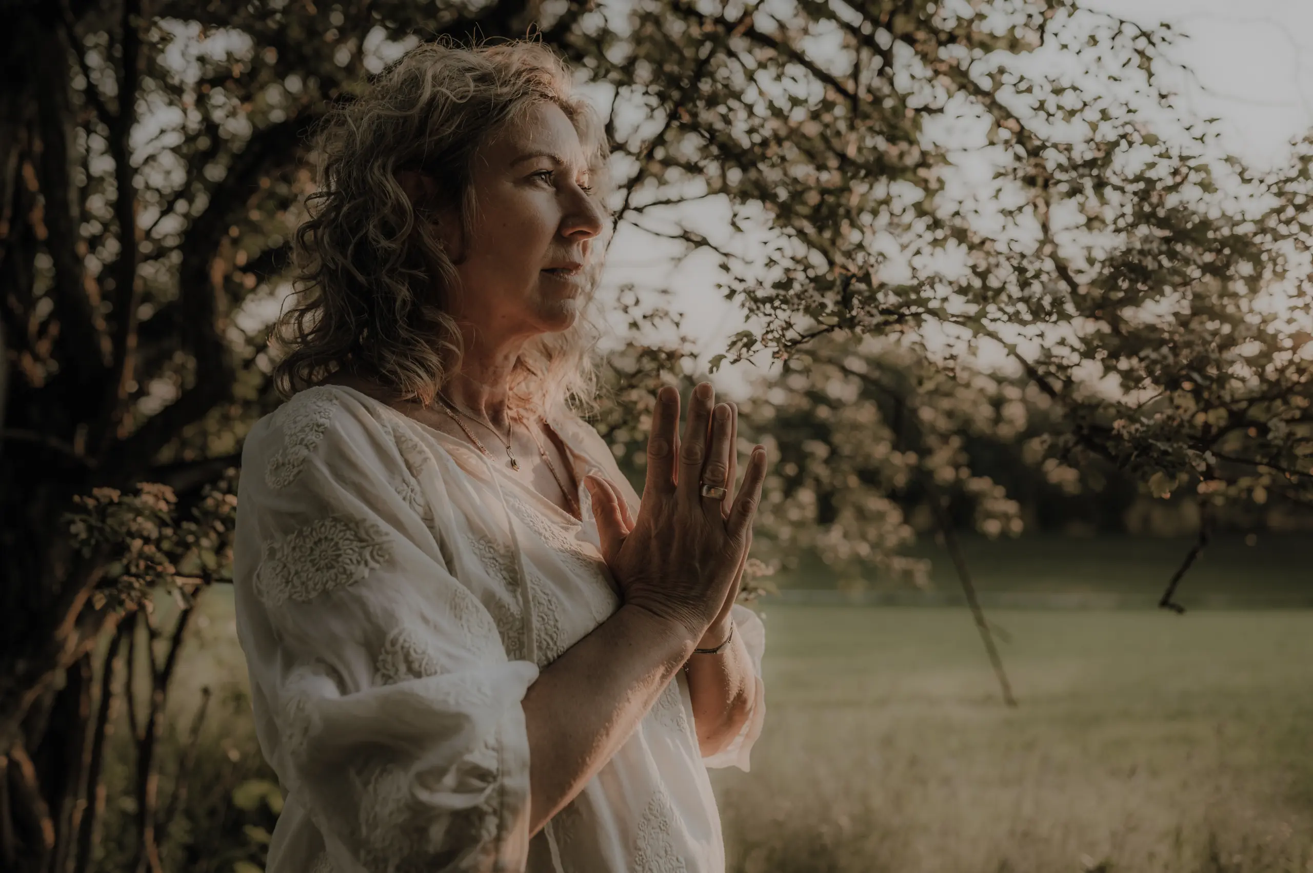 channeling-kurs-ammersee Hildegard Bauer, Channeling Expertin, mit betenden Händen in der Natur bereitet sich auf ihren Kurs vor.