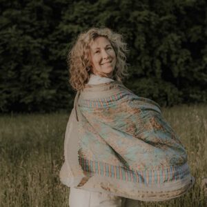 Frau mit großem Tuch fröhlich in der Natur.